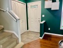 Entryway featuring a white paneled door with decorative glass inserts, ceramic tile flooring, and a built-in storage closet - 184 1804 70 Street, Edmonton, AB 