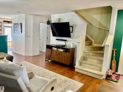 Carpeted staircase with white railings, wood-finish flooring, and white baseboards - 