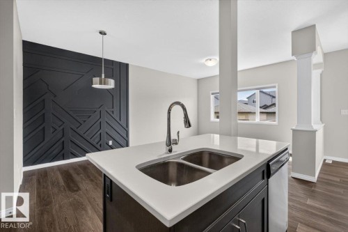 Kitchen island with a double stainless steel sink and gooseneck faucet - 2144 51 Street, Edmonton, AB 