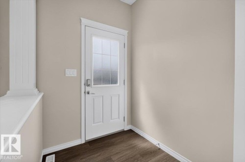 Entry door with clear glass panels, white trim, and dark wood-finish flooring - 2144 51 Street, Edmonton, AB 