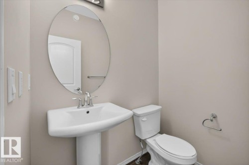 Pedestal sink with chrome faucet, complemented by an oval wall mirror and recessed lighting fixture - 2144 51 Street, Edmonton, AB 