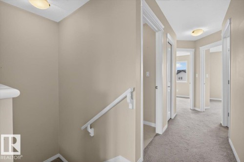 Upper-level landing and hallway featuring light neutral paint, white trim, soft grey carpeting, and multiple doorways - 2144 51 Street, Edmonton, AB 