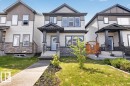 Two-story property featuring a stone and siding facade, covered front entry, concrete pathway, and an arched wooden gate - 2144 51 Street, Edmonton, AB 
