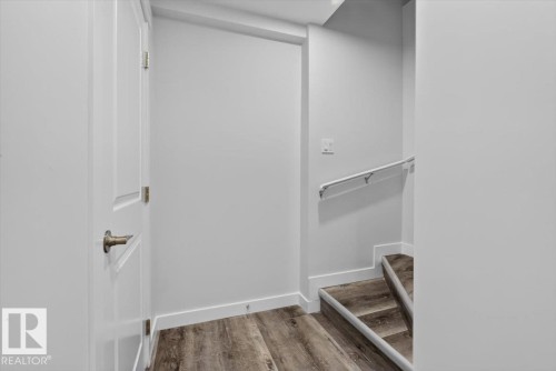 Staircase with wood-finish treads and risers, featuring a white wall-mounted handrail - 2144 51 Street, Edmonton, AB 
