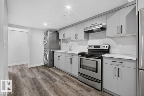 Contemporary kitchen featuring light gray cabinetry, stainless steel appliances, white countertops, and a white tile backsplash - 2144 51 Street, Edmonton, AB 