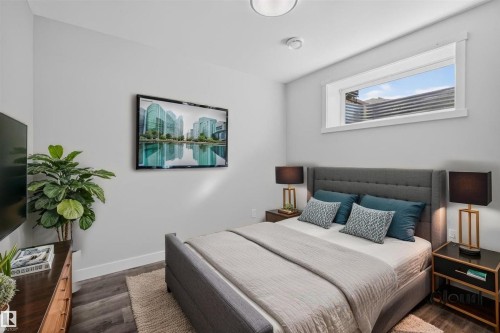 Bedroom featuring a window with white trim, wood-finish flooring, and a flush-mount ceiling light - 2144 51 Street, Edmonton, AB 