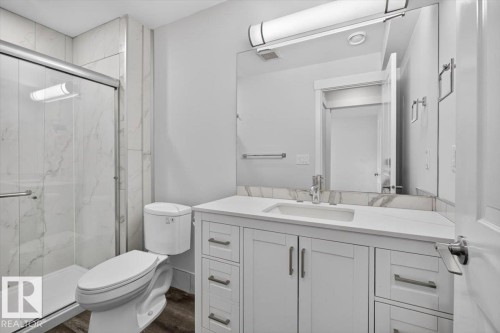 Bathroom featuring a white vanity with an integrated sink, polished chrome faucet, and rectangular mirror - 2144 51 Street, Edmonton, AB 
