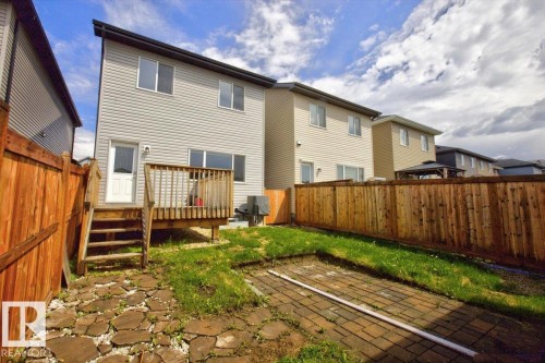 Rear exterior with light gray siding, featuring a wooden deck with railing, a white entry door, and multiple windows - 2144 51 Street, Edmonton, AB 