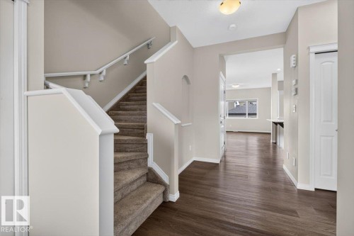 Inviting entryway with dark wood-finish flooring, a carpeted staircase with white trim, and an arched wall niche - 2144 51 Street, Edmonton, AB 