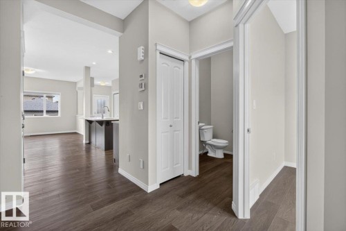 Open concept layout featuring wood-finish flooring, white baseboards, and neutral wall tones - 2144 51 Street, Edmonton, AB 