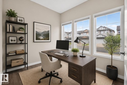 Dedicated workspace featuring three large windows, wood-finish flooring, a neutral wall color, and a built-in shelving unit - 2144 51 Street, Edmonton, AB 
