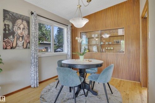 Dining space featuring wood-finish wall paneling with an integrated display cabinet - 9835 74 Street, Edmonton, AB 