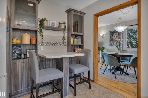 Integrated kitchen cabinetry with glass-front display cabinets, open shelving, and a built-in breakfast bar - 9835 74 Street, Edmonton, AB 