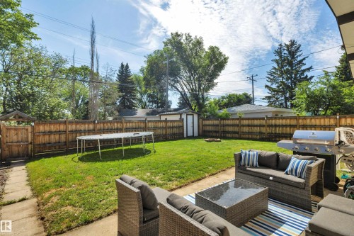 Spacious backyard featuring a manicured lawn, full privacy fencing, and a built-in storage shed - 9835 74 Street, Edmonton, AB 