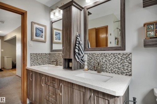 Double vanity with a light-toned countertop, dual rectangular undermount sinks, and a mosaic tile backsplash - 9835 74 Street, Edmonton, AB 