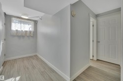 Hallway featuring light wood-finish flooring, light grey painted walls, white baseboards, and a white paneled door - 