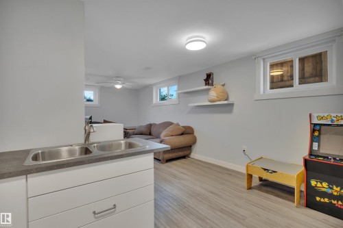 Lower level featuring a dual basin sink with stainless steel faucet, white cabinetry, and a dark countertop - 9835 74 Street, Edmonton, AB 