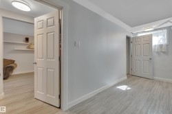 Interior room featuring light wood-finish flooring, light grey walls, and white baseboards - 