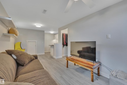 Open-concept living space with light-toned wood-finish flooring, light grey walls, and recessed lighting - 9835 74 Street, Edmonton, AB 