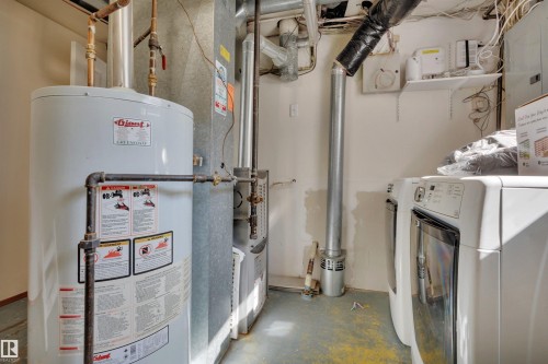 Utility area featuring a water heater, furnace, and laundry appliances - 9835 74 Street, Edmonton, AB 