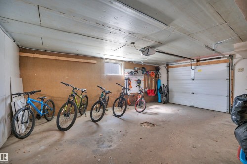 Attached garage featuring a white sectional door, concrete flooring, and a remote-controlled opener - 9835 74 Street, Edmonton, AB 