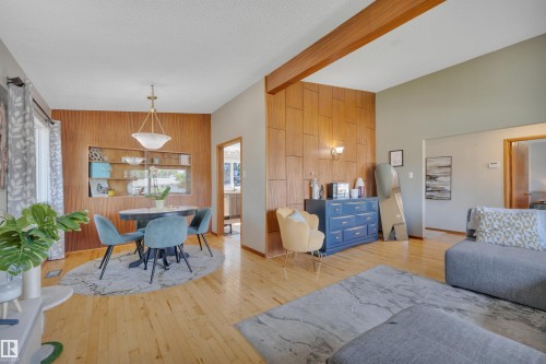 Open-concept living area featuring wood-finish flooring, a vaulted ceiling, and exposed wood ceiling beams - 9835 74 Street, Edmonton, AB 