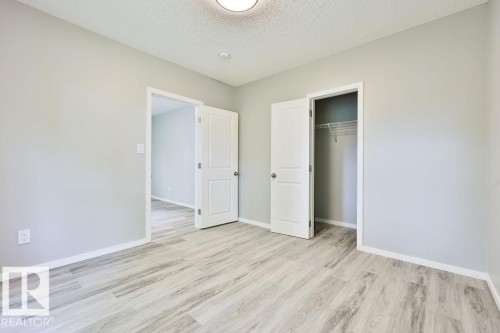 Room featuring light wood-finish flooring, light gray wall paint, white baseboards, and a semi-flush ceiling light fixture - 11241 88 Street, Edmonton, AB 