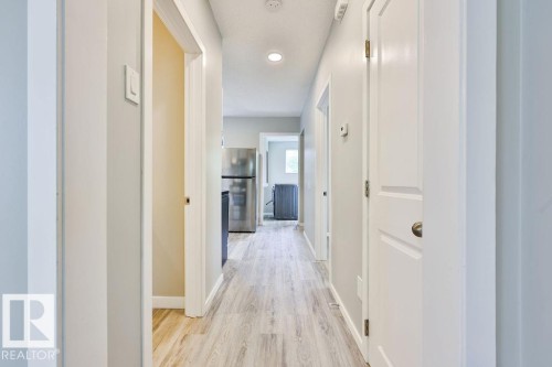 Hallway featuring wood-finish flooring, recessed lighting, and crisp white trim - 11241 88 Street, Edmonton, AB 