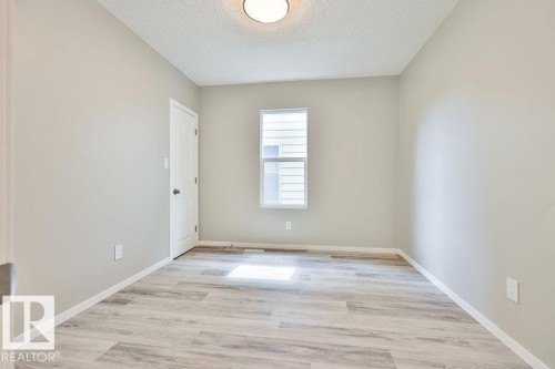 Room featuring light gray walls, wood-finish flooring, a white trim package, and an overhead flush-mount light fixture - 11241 88 Street, Edmonton, AB 