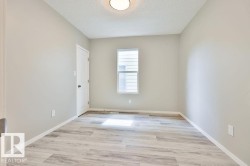 Room featuring light gray walls, wood-finish flooring, a white trim package, and an overhead flush-mount light fixture - 