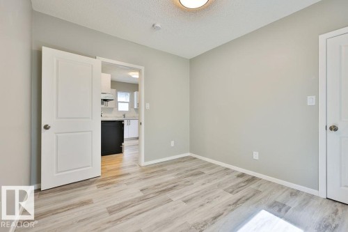 Interior room featuring light wood-finish flooring, neutral-toned walls, and a ceiling-mounted light fixture - 11241 88 Street, Edmonton, AB 