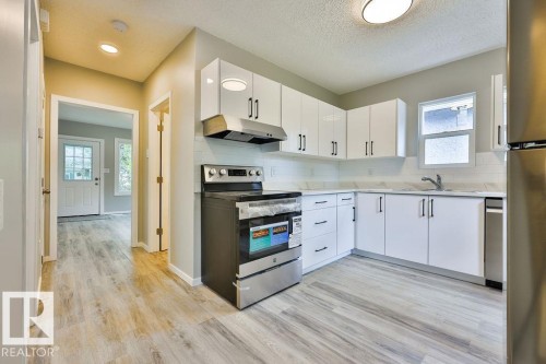 Contemporary kitchen featuring white cabinetry, light-toned countertops, and a subway tile backsplash - 11241 88 Street, Edmonton, AB 