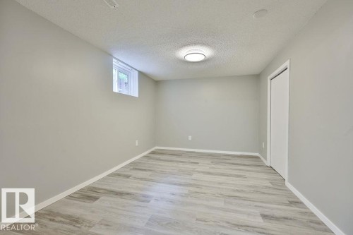 Room featuring wood-finish flooring, light grey walls, white trim, and a flush-mount ceiling light - 11241 88 Street, Edmonton, AB 