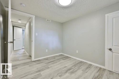 Room featuring light gray walls, wood-finish flooring, white trim, and a flush-mount ceiling light - 11241 88 Street, Edmonton, AB 