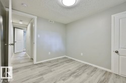 Room featuring light gray walls, wood-finish flooring, white trim, and a flush-mount ceiling light - 