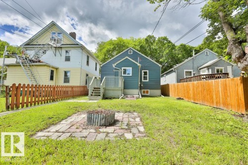 Expansive grass lawn featuring a brick paver patio with a fire pit - 11241 88 Street, Edmonton, AB 