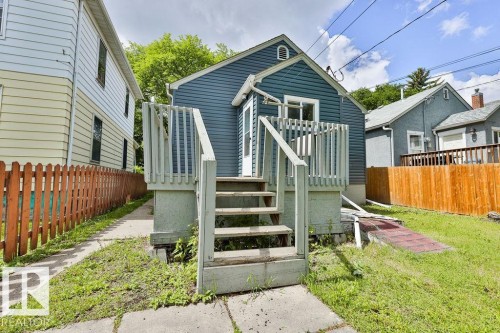 Rear exterior featuring blue horizontal siding, white trim, and a white entry door - 11241 88 Street, Edmonton, AB 