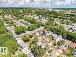 Residential neighborhood featuring mature tree-lined streets, a mix of single-family homes and multi-story structures, paved roads, and fenced yards - 