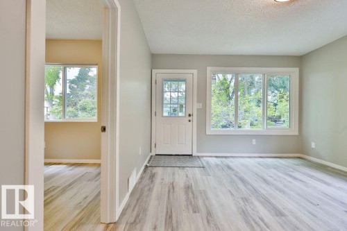 Entryway featuring a white paneled door with glass inserts, wood-finish flooring, and light gray painted walls - 11241 88 Street, Edmonton, AB 