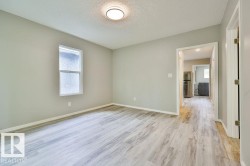 Spacious room featuring wood-finish flooring, light gray wall paint, and a single window with white trim - 