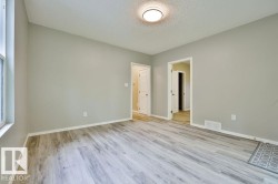 Spacious room featuring light wood-finish flooring, neutral gray wall paint, and white trim - 