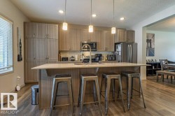 Kitchen featuring a central island with countertop seating, stainless steel appliances, wood-finish flooring, recessed lighting, and pendant lighting fixtures - 
