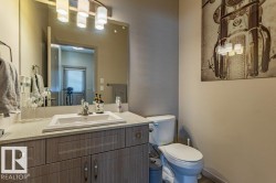 Bathroom featuring a wood-finish vanity with an integrated sink, a large wall mirror, and a multi-light fixture - 