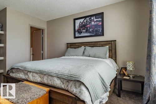 Spacious bedroom featuring neutral wall tones, a wood-finish bed frame with an integrated headboard, and soft gray carpeting - 17123 49 Street, Edmonton, AB 