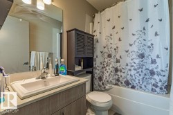 Bathroom featuring a built-in vanity with an integrated sink, a large wall-mounted mirror, a tub-shower combination, and a wall-mounted storage cabinet - 