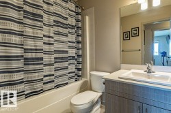 Bathroom featuring a tub/shower combination, white toilet, and a vanity with a light-colored countertop - 