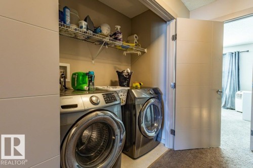 Dedicated laundry closet featuring a stacked washer and dryer, wire shelving, and a modern paneled door - 17123 49 Street, Edmonton, AB 