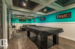 Spacious recreation area featuring wood-finish flooring, a coffered ceiling with recessed lighting, and wainscoting - 