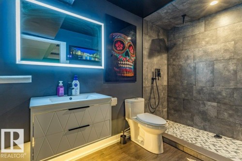 Contemporary bathroom featuring a floating vanity with integrated sink, illuminated mirror, and wood-finish flooring - 17123 49 Street, Edmonton, AB 
