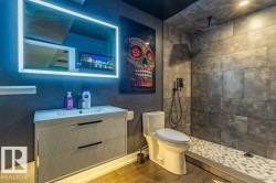 Contemporary bathroom featuring a floating vanity with integrated sink, illuminated mirror, and wood-finish flooring - 